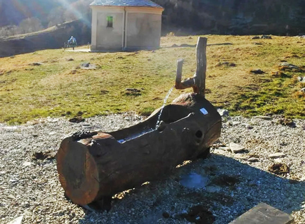 Pian Gurài è circondato dall’acqua, ma è distante. Duecento metri di tubo e la maestria di Beppe di San Culët nel 2003 rimediano alla mancanza. Ora accanto alla chiesa un rubinetto spande acqua in un grosso tronco di larice. Abbeveratoio per le mucche e ristoro per gli uomini. (Foto Guido Ostorero 3 dicembre 2015)